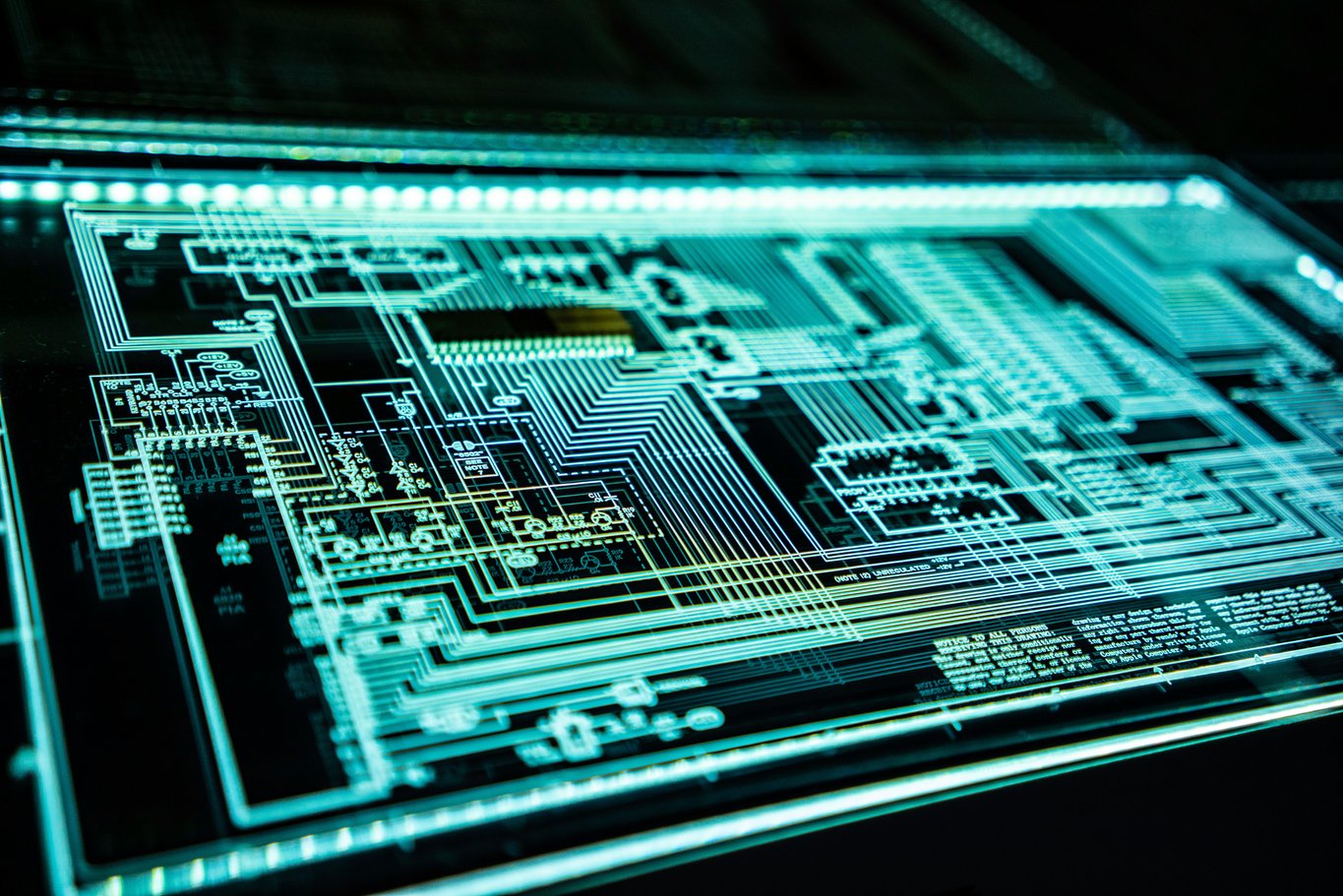 A dense circuit schematic drawing lit in glowing turquoise on a dark backlit panel